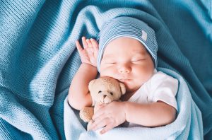 Un genitore che cuce una coperta per il proprio bambino affetto da un deficit ormonale tiroideo mentre riposa Una toccante fotografia che ritrae un neonato che dorme sereno tra le braccia di una persona tenera