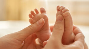 Un bambino con anomalie congenite multiple riceve un massaggio delicato al dito sulla mano, una parte importante del suo corpo