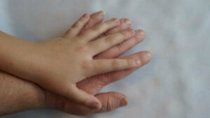 Un bambino che gode di un massaggio al polso, con la sudorazione assente una mano con lunghia del dito che conferisce un tocco speciale alla pelle