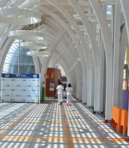 Un uomo con distrofia muscolare congenita cammina su un lungo corridoio allinterno di un edificio moderno, con architettura e design dinterni che caratterizzano la terminale aeroportuale