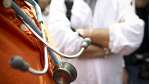 Un uomo adulto maschio indossa una giacca da medico e un stetoscopio, un simbolo della sua professione come medico specializzato nella cura della distrofia muscolare congenita