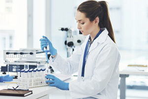 Una donna adulta indossa una giacca da laboratorio mentre indossa un guanto per testare la cistinuria congenita in un laboratorio